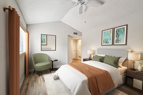 A bedroom with a large bed and a green chair.