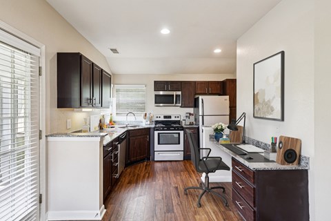 A kitchen with dark brown cabinets and white appliances.