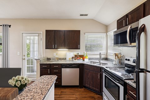 A kitchen with dark wood cabinets and stainless steel appliances.