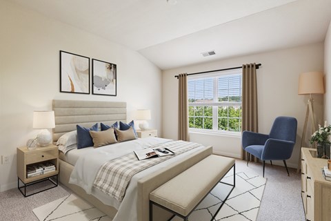 A bedroom with a large bed, a chair, and a window with blinds.