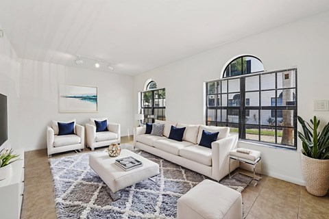 A living room with white furniture and a large window.