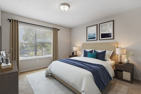 A bedroom with a large bed and a window with blinds.