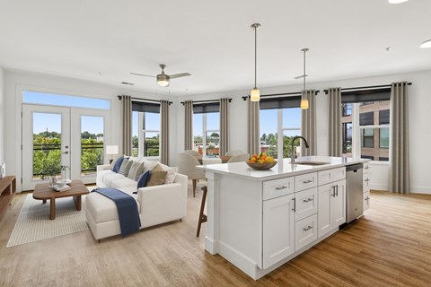 A modern living room with a white sofa and a kitchen area in the background.