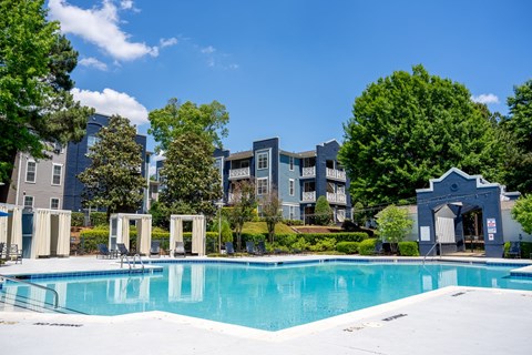 A swimming pool in front of a building with trees around.