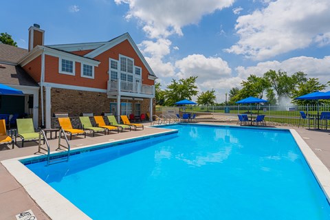 A large blue swimming pool in front of a red brick house.