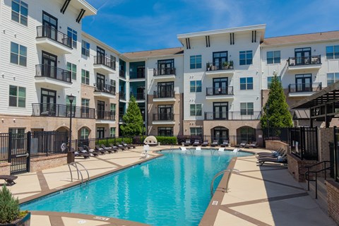 A large swimming pool is surrounded by apartment buildings.