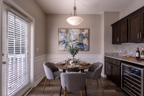 A dining room with a table set for two and a painting on the wall.