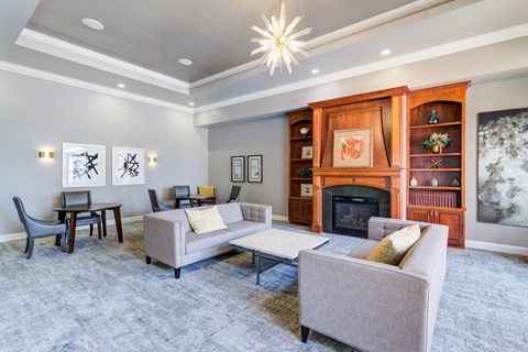 A living room with a grey couch, a chair, a table, a fireplace, and a painting on the wall.