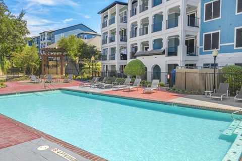 A swimming pool surrounded by a red brick border and a wooden fence.
