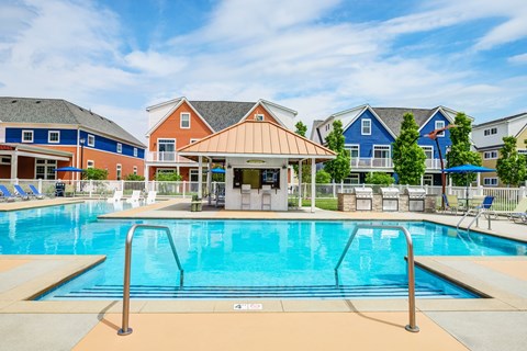 A pool with a diving board and a building in the background.