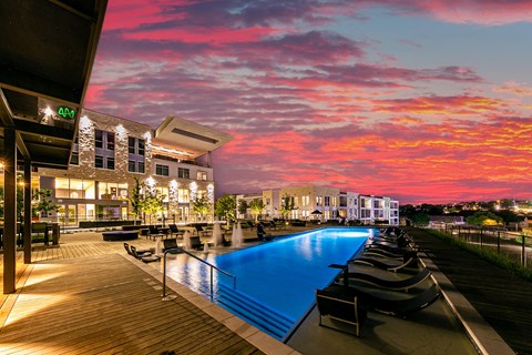 A pool area with a sunset sky in the background.