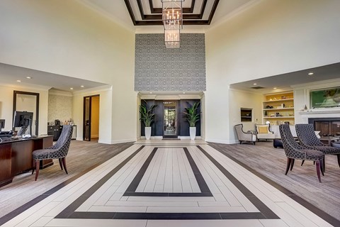 A spacious living room with a large rug and a chandelier.