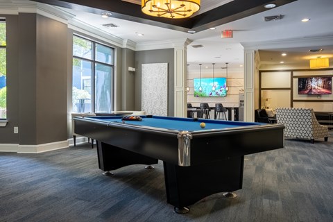 A pool table in a room with a television and a patterned chair.