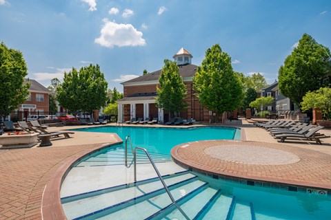 A large swimming pool with a diving board and a building in the background.