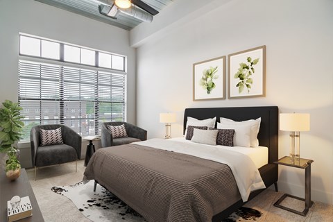 A bedroom with a large bed and two chairs.