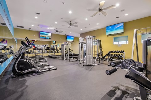 A gym with a variety of equipment including treadmills, weights, and exercise machines.