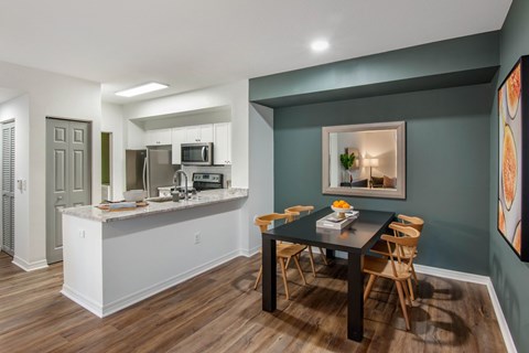 A kitchen with a breakfast bar and a dining table with chairs.