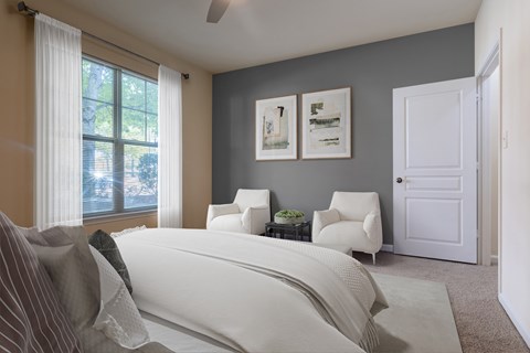A bedroom with a large bed and two chairs.