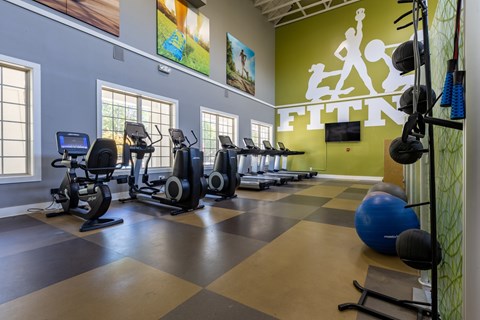 A gym with a green wall that says Fitness.