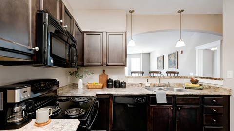 A kitchen with a black stove top oven and black microwave.