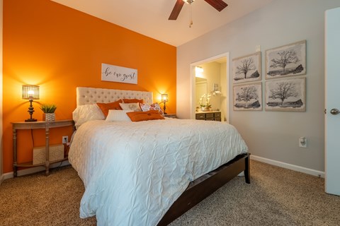 A bedroom with a white bed and a ceiling fan.