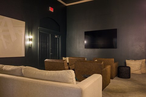 A living room with a white couch and a flat screen TV mounted on the wall.