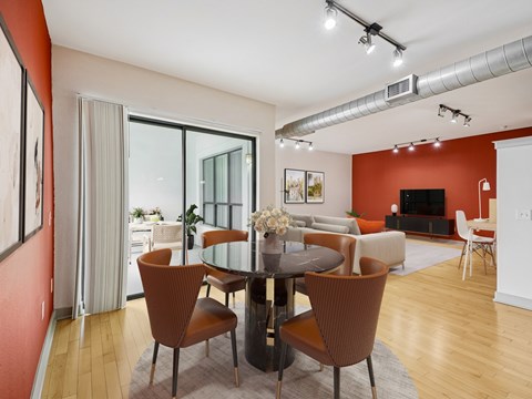 A modern dining room with a glass table surrounded by brown chairs.