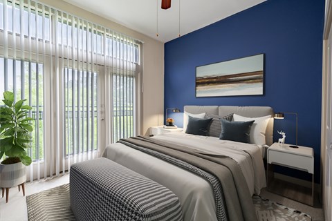 A bedroom with a large bed and a plant by the window.