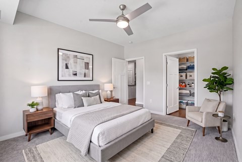 A bedroom with a large bed, a ceiling fan, and a chair.