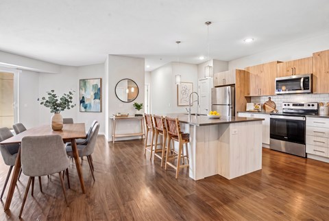 A modern kitchen with wooden floors and furniture.