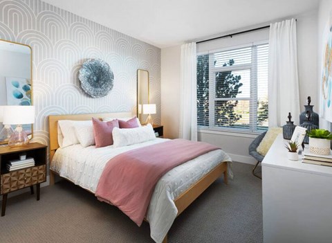 A bedroom with a large bed and a window with blinds.