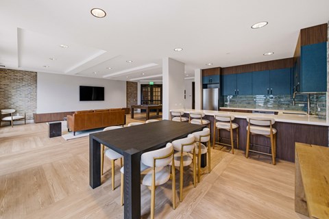A modern kitchen with a long black table and white chairs.