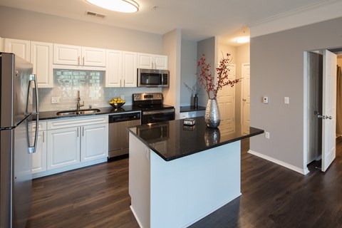 A kitchen with white cabinets and a black island.