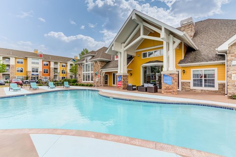 A large swimming pool in front of a yellow building.