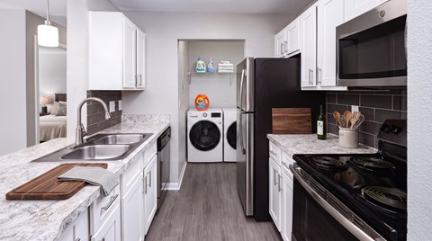 A modern kitchen with white cabinets and a black stove top.