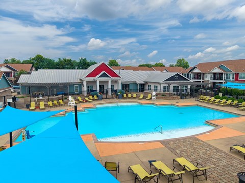 A large outdoor swimming pool surrounded by sun loungers and umbrellas.