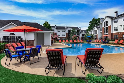 A poolside area with chairs and an umbrella.