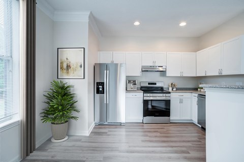 A modern kitchen with white cabinets and stainless steel appliances.