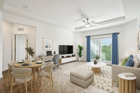 A living room with a television, a dining table with chairs, and a couch with pillows.