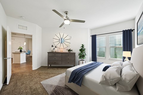 A bedroom with a bed, dresser, and ceiling fan.