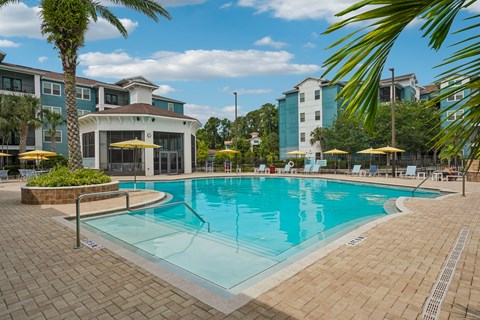 A large swimming pool surrounded by palm trees and lounge chairs.