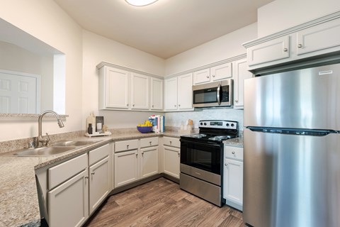A kitchen with a stainless steel refrigerator, sink, and cabinets.