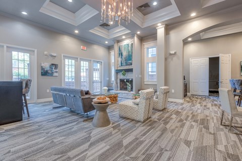A living room with a grey carpet and a chandelier.