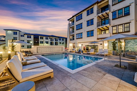 A large outdoor pool surrounded by lounge chairs and umbrellas.