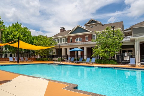 A large swimming pool with a yellow canopy and a building in the background.