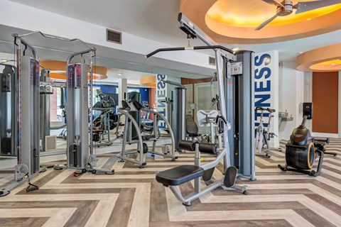 A gym with a variety of equipment including treadmills, weights, and exercise machines.