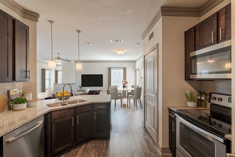 A modern kitchen with dark wood cabinets and stainless steel appliances.
