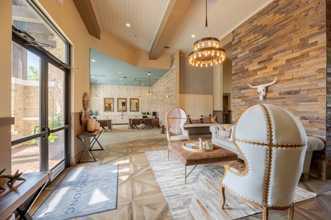 A living room with a white chair and a stone wall.