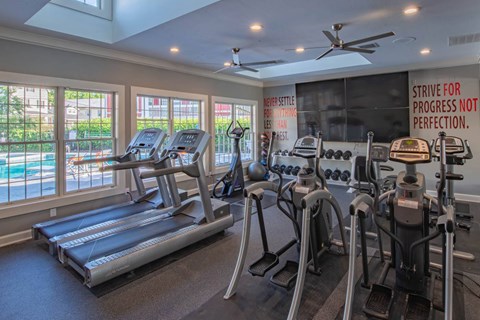 A gym with treadmills, elliptical machines, and a motivational poster.