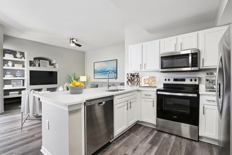 A modern kitchen with white cabinets and stainless steel appliances.